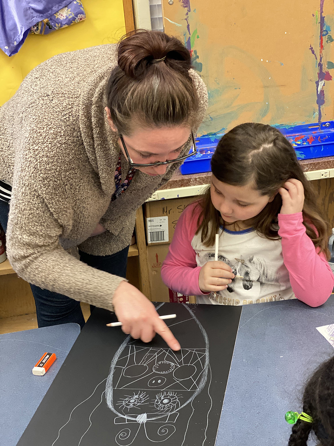 A woman and a student look at a piece of art.
